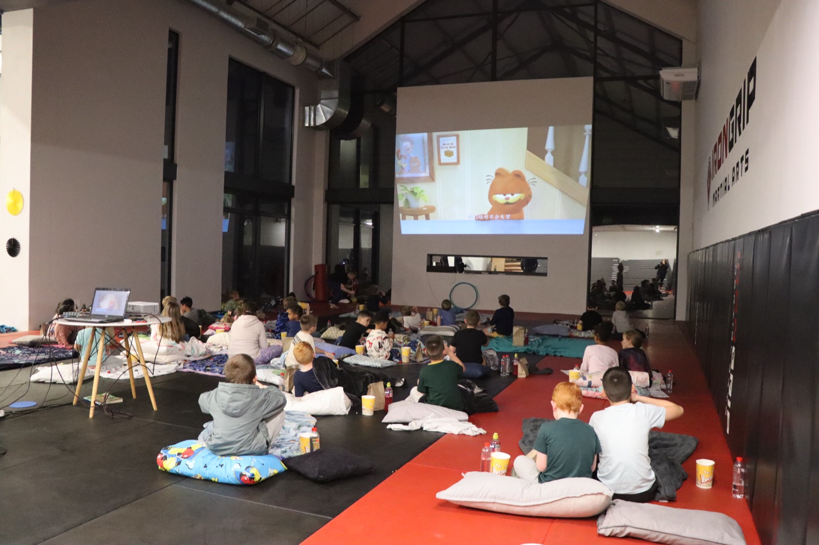 Children in pajamas watching a movie on the big screen